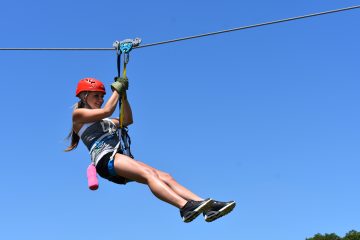 Girl using the braking system on a ziplinie above the trees